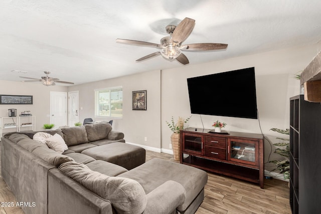 living room featuring light wood-style floors, ceiling fan, and baseboards