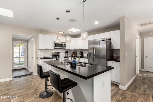 kitchen with dark countertops, visible vents, stainless steel appliances, and a sink