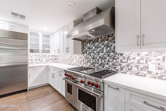 kitchen with white cabinetry, wall chimney range hood, decorative backsplash, and high end appliances