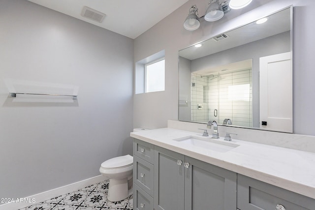 bathroom featuring a shower with shower door, vanity, tile patterned flooring, and toilet