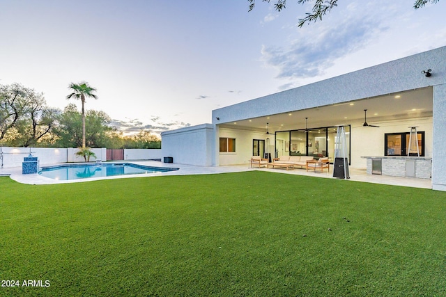 rear view of property with a lawn, ceiling fan, a fenced in pool, outdoor lounge area, and a patio