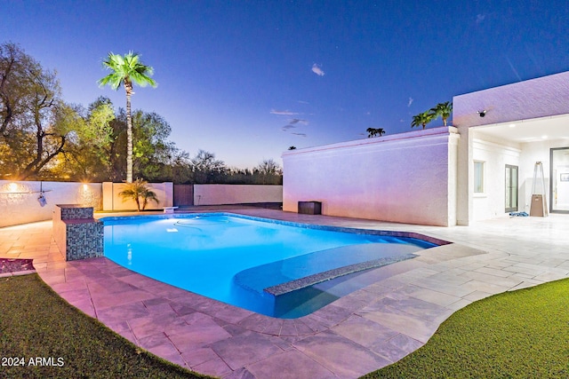 pool at dusk featuring a patio area