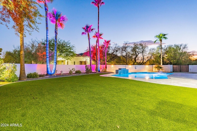 yard at dusk featuring a fenced in pool and a patio