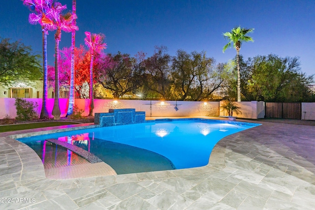 pool at dusk featuring a patio