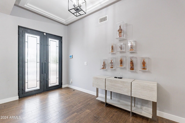 foyer featuring dark hardwood / wood-style flooring, ornamental molding, french doors, and a raised ceiling