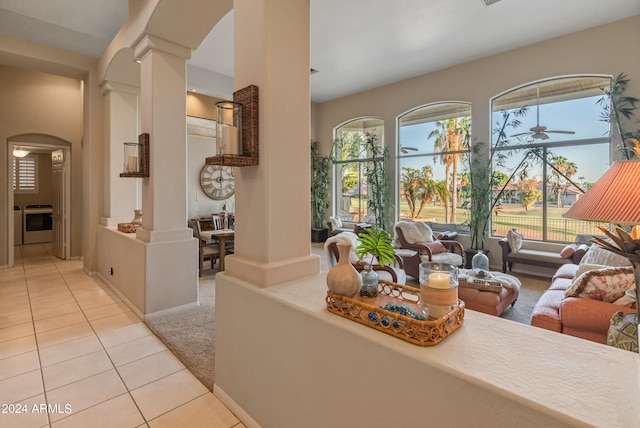 living room featuring decorative columns, light tile patterned flooring, and a healthy amount of sunlight