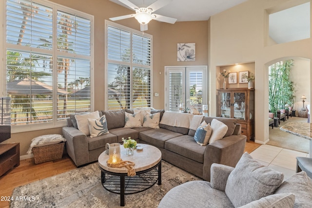 living room featuring a high ceiling, ceiling fan, plenty of natural light, and light hardwood / wood-style flooring