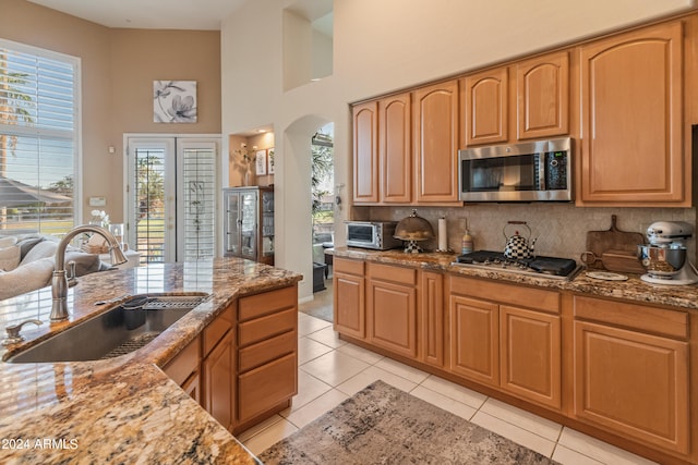 kitchen featuring light stone countertops, light tile patterned flooring, stainless steel appliances, and sink