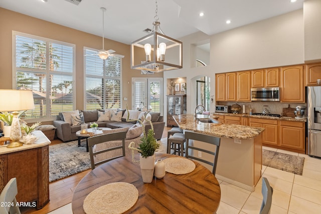 dining space featuring an inviting chandelier, light hardwood / wood-style flooring, sink, and a high ceiling