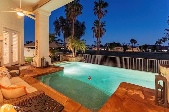 pool at night with a jacuzzi and a patio area