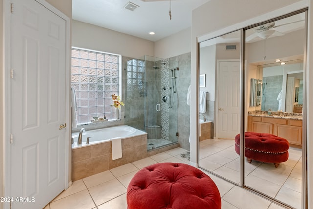 bathroom with plus walk in shower, ceiling fan, tile patterned flooring, and vanity