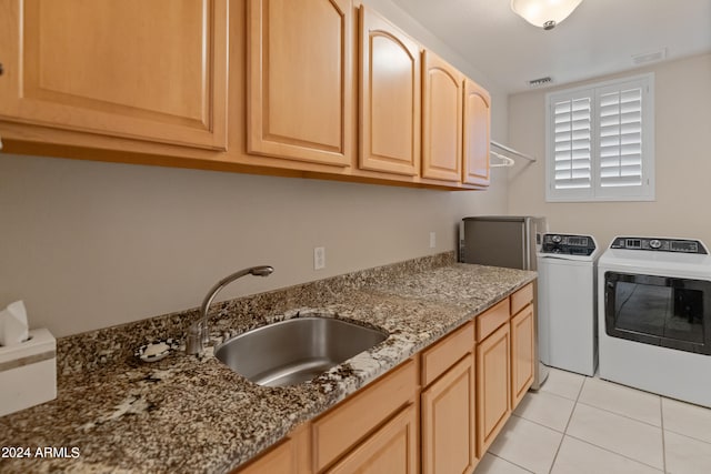 clothes washing area with washing machine and dryer, cabinets, sink, and light tile patterned floors