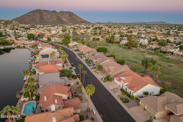 aerial view at dusk featuring a water and mountain view