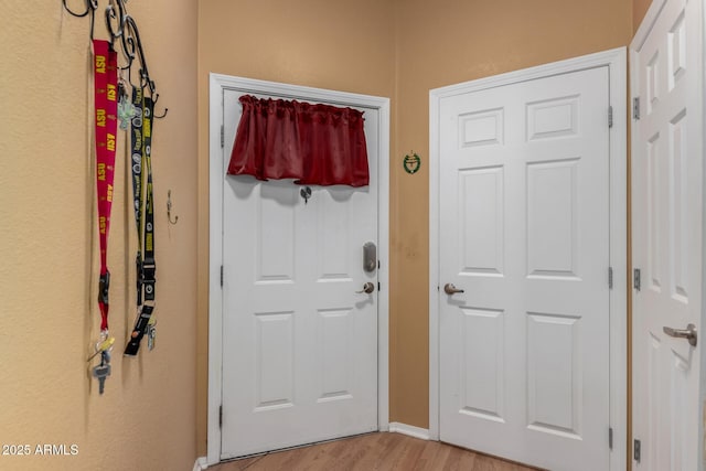 doorway featuring light wood-style flooring and baseboards