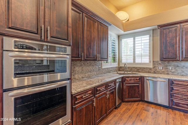 kitchen with light stone countertops, decorative backsplash, stainless steel appliances, and sink