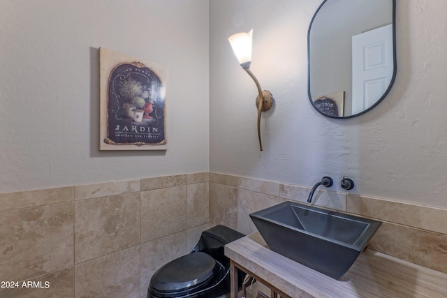 bathroom with toilet, tile walls, and sink