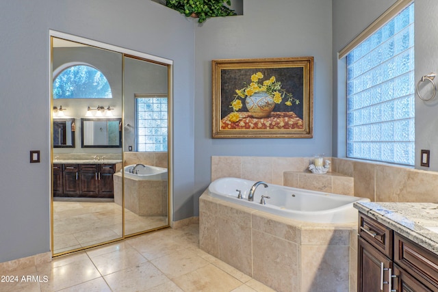 bathroom featuring tile patterned flooring, vanity, and tiled bath