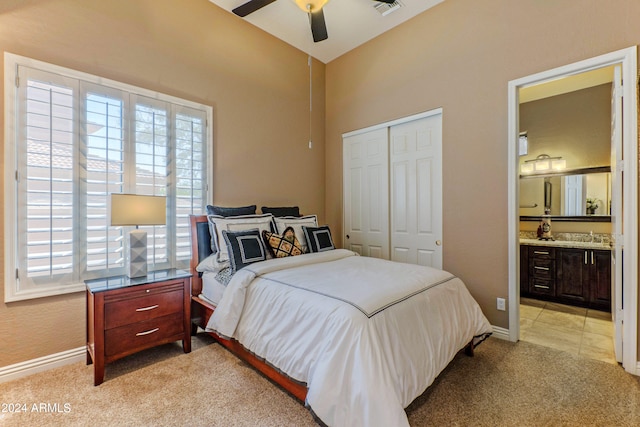 bedroom with ceiling fan, light colored carpet, ensuite bathroom, and a closet