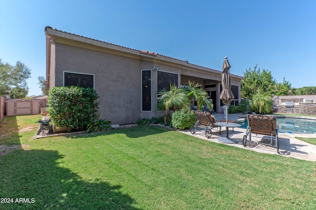 rear view of house with a fenced in pool, a storage shed, a patio area, and a lawn