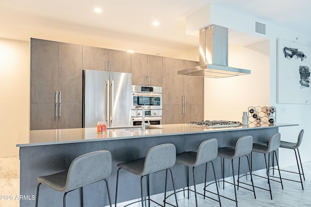 kitchen featuring stainless steel appliances, a kitchen bar, marble finish floor, and island range hood