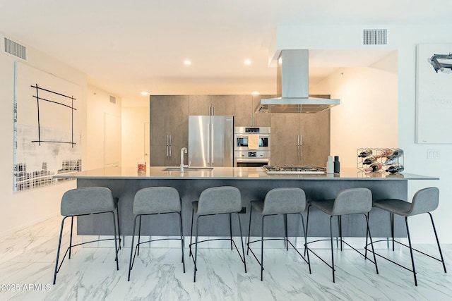 kitchen featuring island exhaust hood, visible vents, appliances with stainless steel finishes, and a breakfast bar area