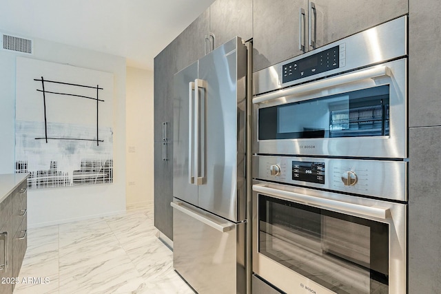 kitchen featuring baseboards, visible vents, stainless steel appliances, modern cabinets, and marble finish floor