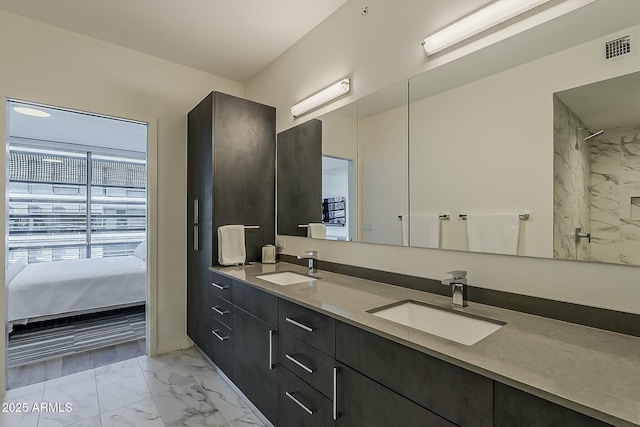 bathroom with ensuite bath, double vanity, marble finish floor, and a sink