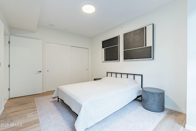 bedroom with a closet, baseboards, and light wood-style floors