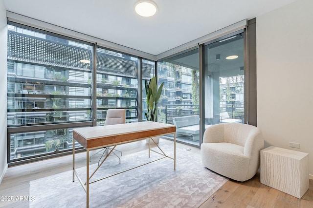 home office featuring a wall of windows and wood finished floors