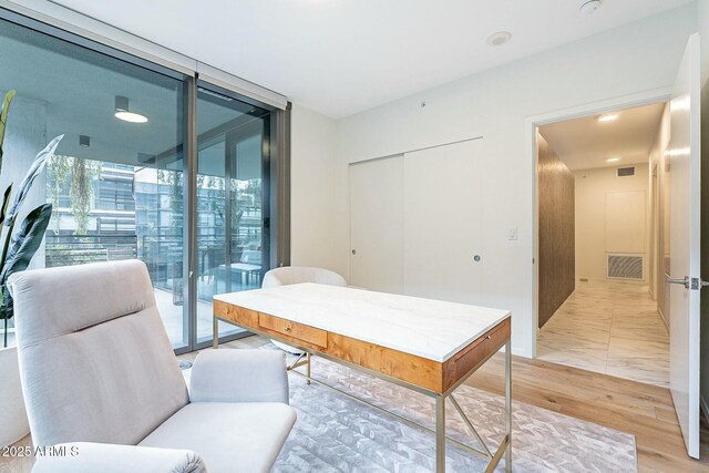office space featuring visible vents, floor to ceiling windows, and light wood-style floors