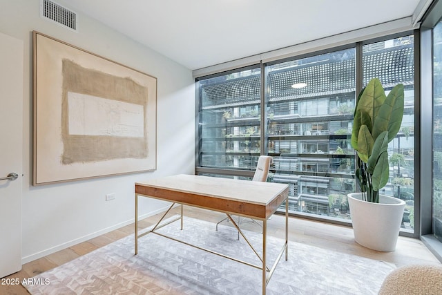 office space featuring visible vents, wood finished floors, baseboards, and expansive windows