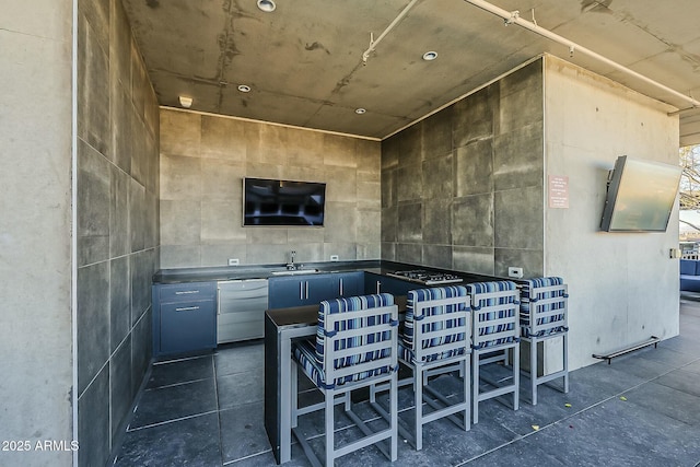 bar with dark tile patterned floors, dishwasher, tile walls, gas cooktop, and a sink