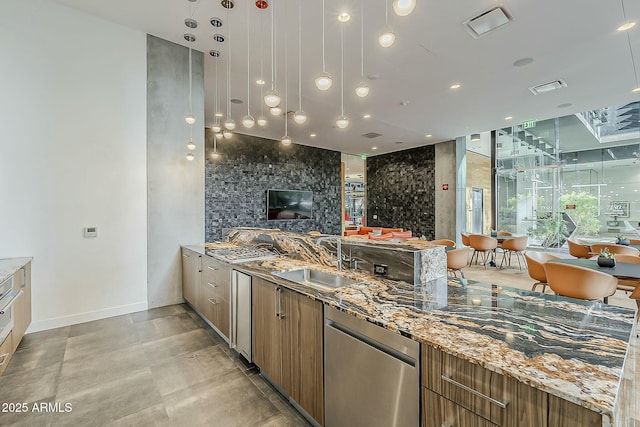 kitchen featuring visible vents, open floor plan, light stone counters, modern cabinets, and a sink