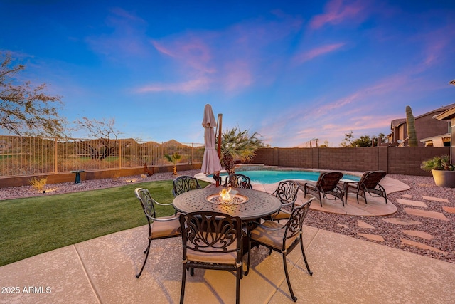 patio terrace at dusk featuring a fenced in pool and a lawn