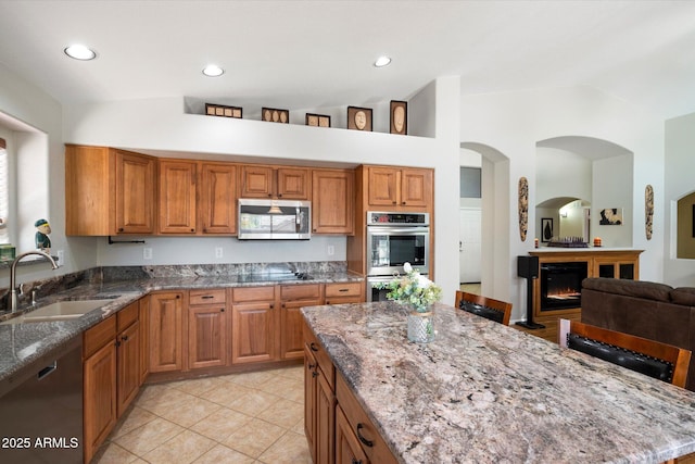 kitchen with light stone counters, appliances with stainless steel finishes, and a sink