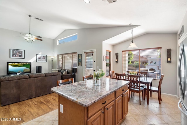 kitchen featuring light tile patterned floors, a kitchen island, vaulted ceiling, and hanging light fixtures