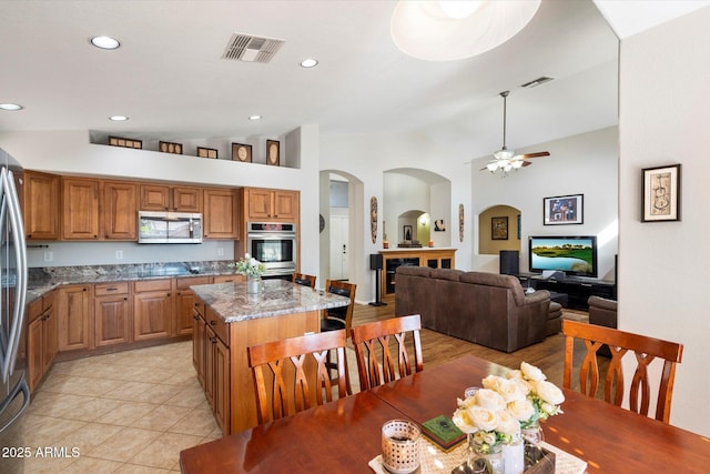 kitchen featuring light stone counters, visible vents, appliances with stainless steel finishes, and a center island