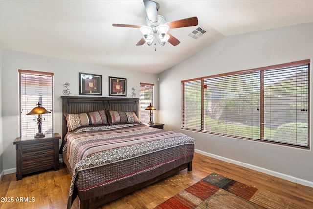 bedroom featuring wood finished floors, visible vents, baseboards, lofted ceiling, and ceiling fan