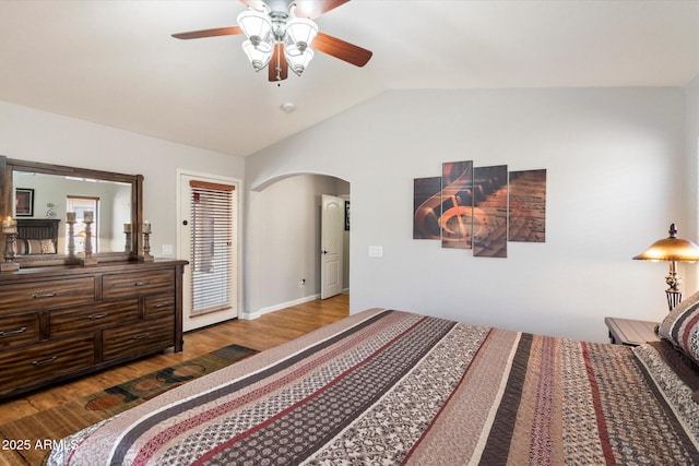 bedroom with arched walkways, wood finished floors, a ceiling fan, and vaulted ceiling