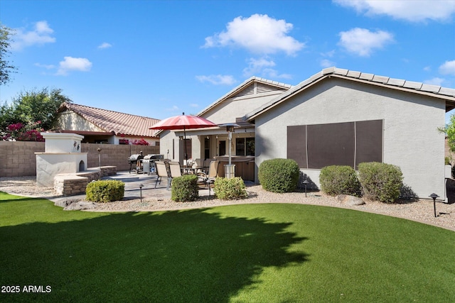 back of house with fence, stucco siding, a hot tub, a patio area, and a lawn