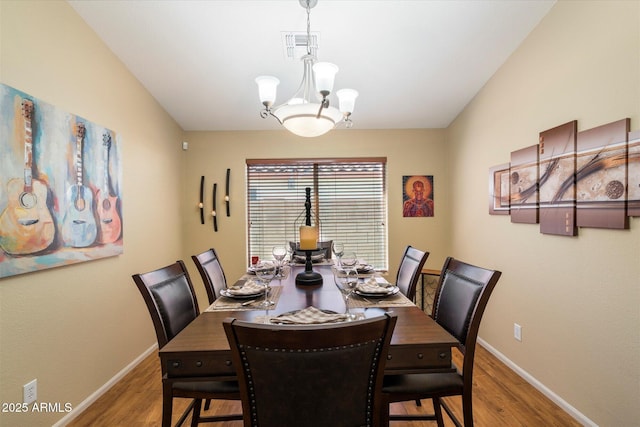 dining room with a chandelier, visible vents, baseboards, and wood finished floors