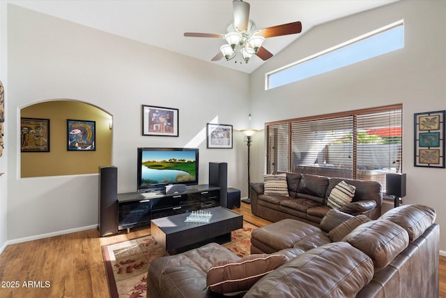 living room featuring ceiling fan, wood finished floors, baseboards, and high vaulted ceiling