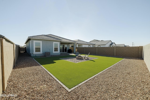 back of property with a lawn, a patio area, and a fire pit