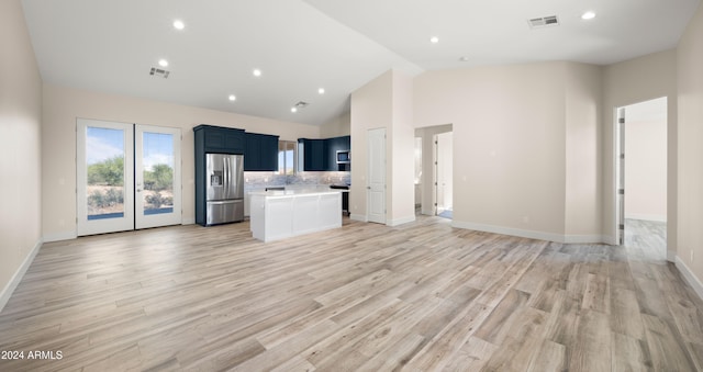 unfurnished living room with french doors, high vaulted ceiling, and light wood-type flooring