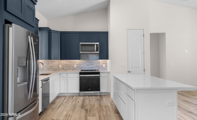 kitchen with stainless steel appliances, backsplash, sink, light stone countertops, and light wood-type flooring