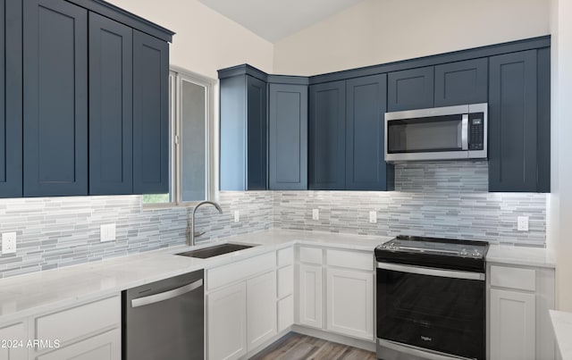 kitchen with backsplash, appliances with stainless steel finishes, white cabinetry, light wood-type flooring, and sink