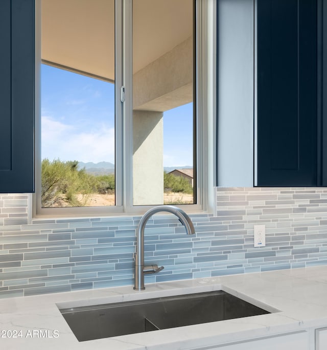 interior details with tasteful backsplash, light stone countertops, sink, blue cabinets, and a mountain view