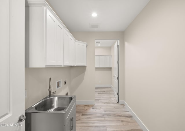 kitchen with light hardwood / wood-style floors, sink, and white cabinets