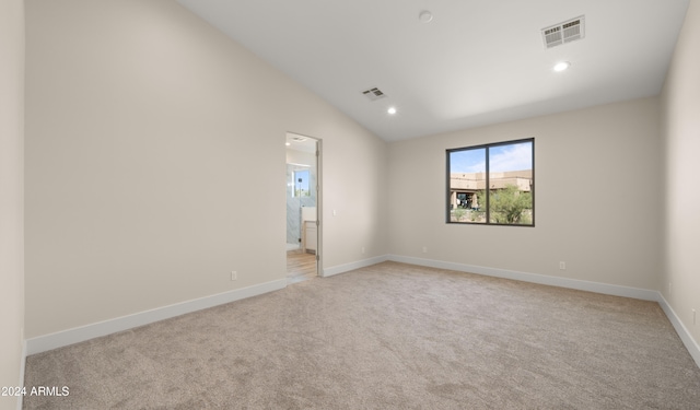 carpeted spare room with vaulted ceiling