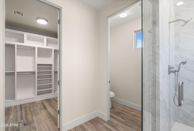 bathroom featuring a shower with door, toilet, and wood-type flooring